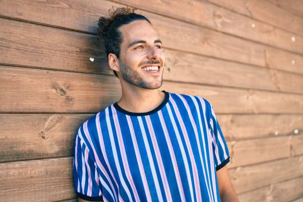 istock Young hispanic man smiling happy looking to the side leaning on the wall. 1346578123
