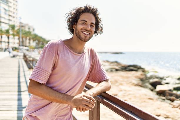 istock Young hispanic man smiling happy standing at the beach. 1346578146