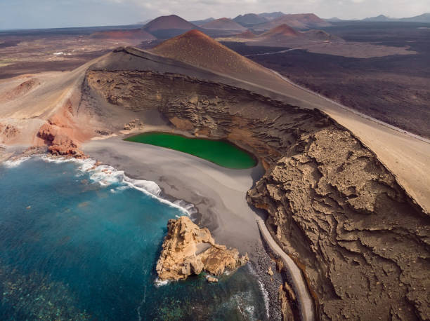 cráter volcánico con un lago de cráter cerca de el golfo, isla de lanzarote. vista aérea - isla de lanzarote fotografías e imágenes de stock