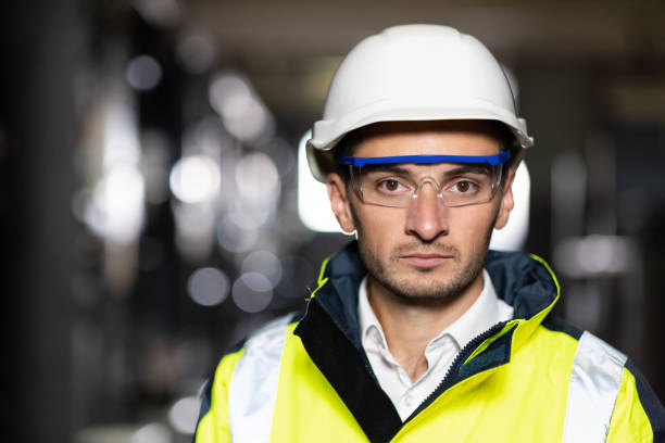 istock Professional Confident Serious Engineer Looking at Camera, Wearing Safety Uniform and Goggles Standing at Heavy Industry Factory Ready to Manufacturing Works During Metal Welding by Staff 1346578394
