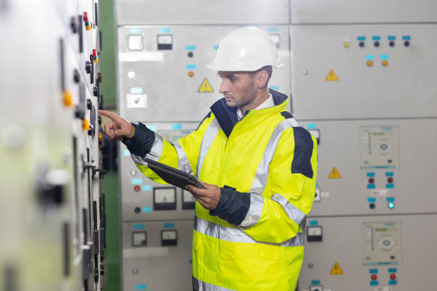 istock Man electrical engineer hold tablet monitoring electrical system in control room. Technician inspect to control panel screen system for generate electricity of factory in manufacture industrial 1346578589