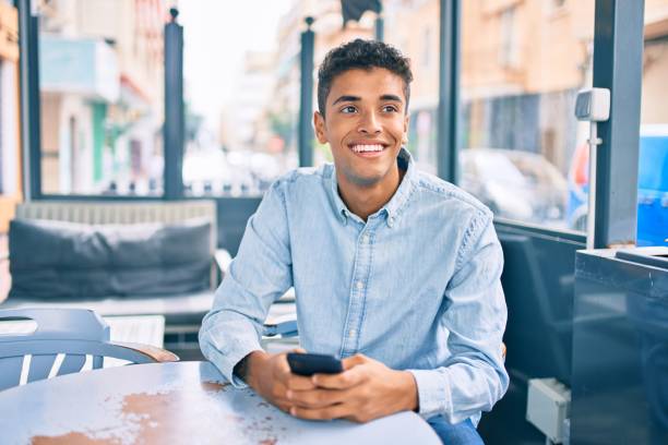 istock Young latin man smiling happy using smartphone at coffee shop terrace. 1346578628