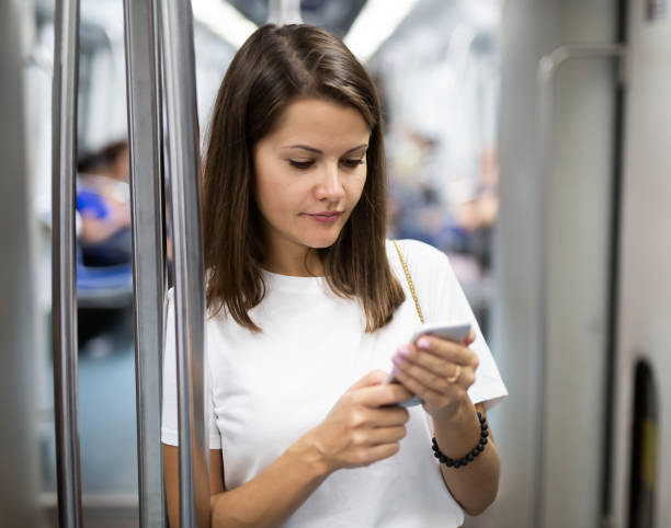 istock Female using mobile phone in subway car 1346580274