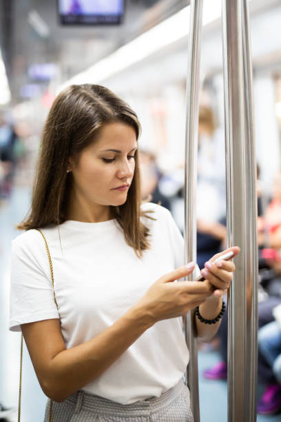 istock Woman using phone in subway car 1346580276