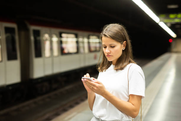 istock Woman waiting subway car using phone 1346580294