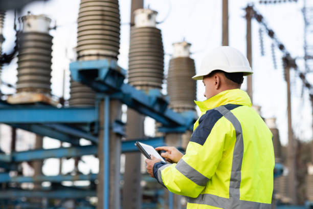 elektroingenieur studiert lesen auf tablet. elektroarbeiter ingenieur eine arbeit mit digitalen tablet, strom in der nähe von turm mit strom. energiewirtschaftliches technologie-branchenkonzept - umspannwerk stock-fotos und bilder