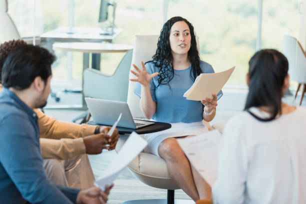 istock Female team lead gestures during presentation to diverse employees 1346582427