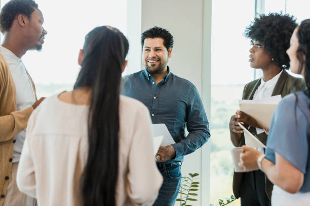 istock Co-workers stand and talk together before meeting 1346582453