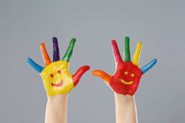 istock Kid with smiling faces drawn on palms against grey background, closeup 1346584925
