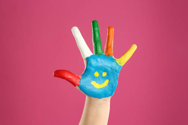 istock Kid with smiling face drawn on palm against pink background, closeup 1346585128