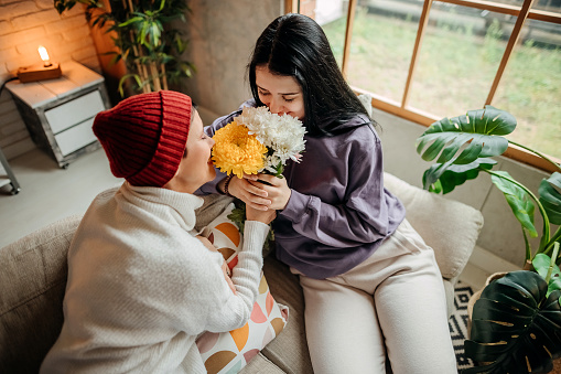 Mother and her cute daughter with bouquet of yellow tulips at home. Space for text