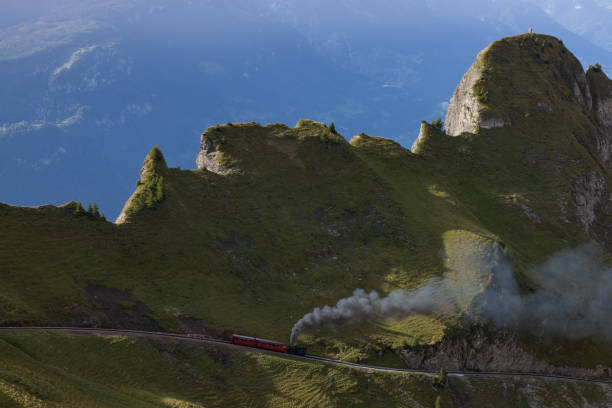 incredibile giornata di escursioni nelle alpi della svizzera. una bella locomotiva si dirige verso una montagna e un sacco di fumo esce dalla locomotiva. che vista sullo sfondo. - lake thun swiss culture switzerland berne foto e immagini stock