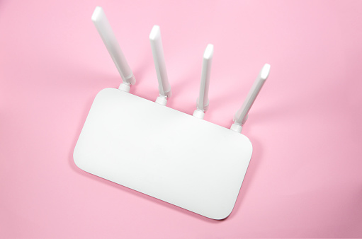 White Modern Wi-Fi router on the pink background. Wireless ethernet connection signal.