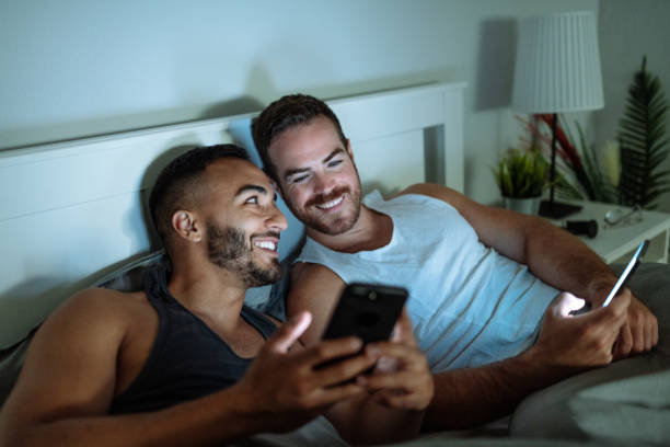 istock Gay couple in bedroom using social networks before going to sleep 1346592964