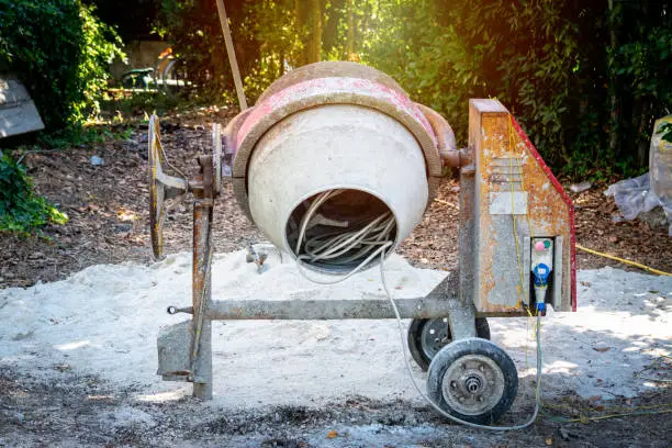 DIrty concrete mixer in a garden at sunset