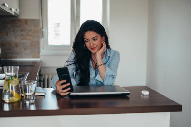 businesswoman taking selfie with her smartphone while sitting in her kitchen at home - güneş videolar stok fotoğraflar ve resimler