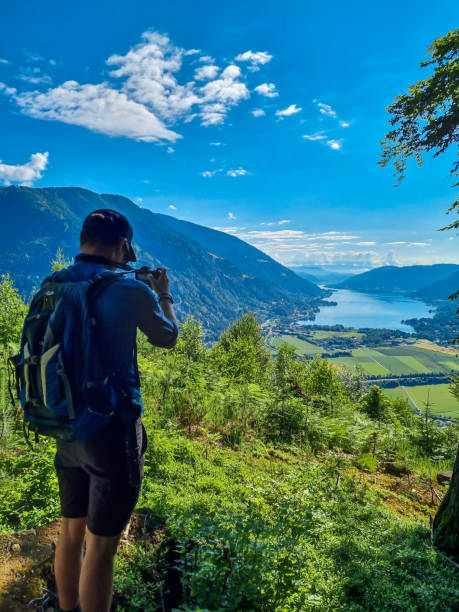 oswaldiberg - un hombre tomando fotos cerca de la cima de oswaldiberg con la vista sobre el lago ossiach, carintia, austria. fotografía - cordillera karavanke fotografías e imágenes de stock