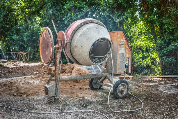 Concrete mixer, sand and gravel in a green garden