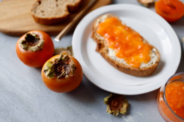 istock Whole persimmons on a gray rough concrete floor and persimmon paste spread on buttered bread 1346596010
