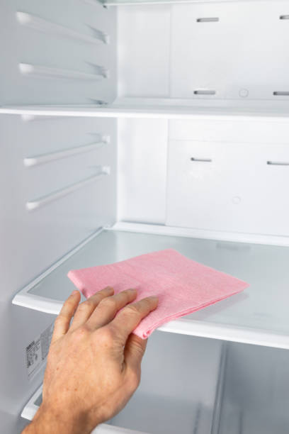 istock Man's hand cleaning fridge. Regular cleaning home refrigerator inside. 1346596231