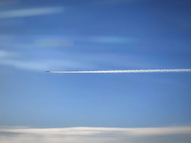 plane in the blue sky over coluds with contrails