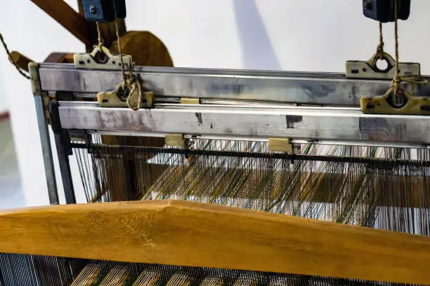 Photo of The top of an old loom with wooden and metal parts.