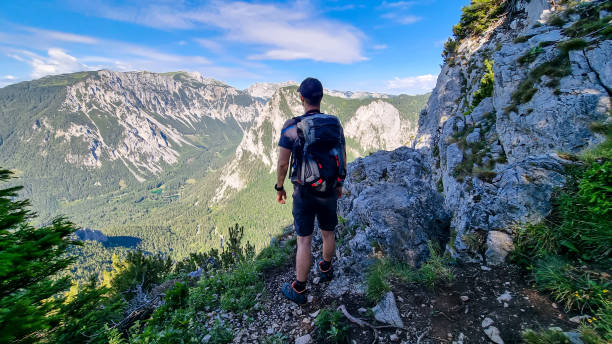 istock Messnerin - A man with a hiking backpack standing on the rock with a view on the Alpine mountain chains in Styria, Austria 1346597706