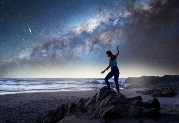 istock unknown woman standing on the beach with Milky Way background 1346603494
