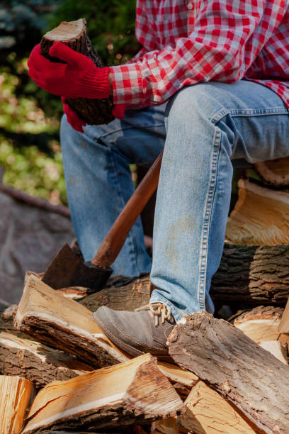 Lumberjack with big ax sits on pile of firewood stock photo