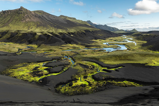 This valley with bright green moss and black volcanic soil is on the road that leads to Landmannalauger in the Highlands of Iceland
