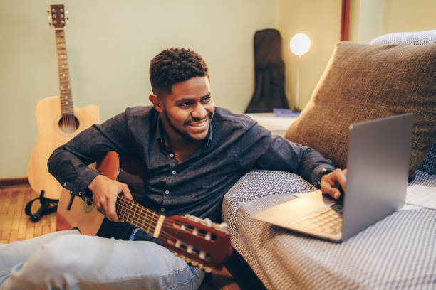 istock Young African-American practice playing guitar at home 1346609199