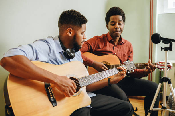 istock Two young African-Americans playing musical instruments at home 1346609362