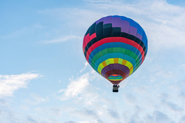 istock Multicolored hot air balloon on blue cloudy sky background 1346609901