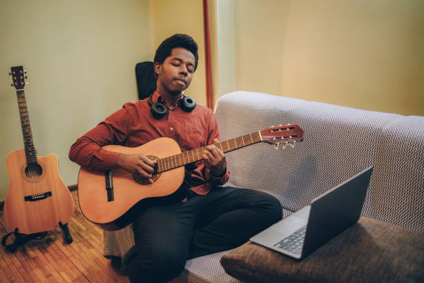 istock Young African-American playing guitar at home 1346610311