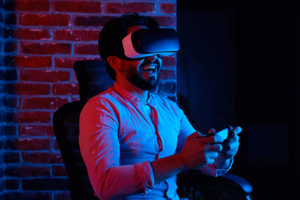 istock Excited man smiling while playing games in VR glasses, sitting on chair 1346611333
