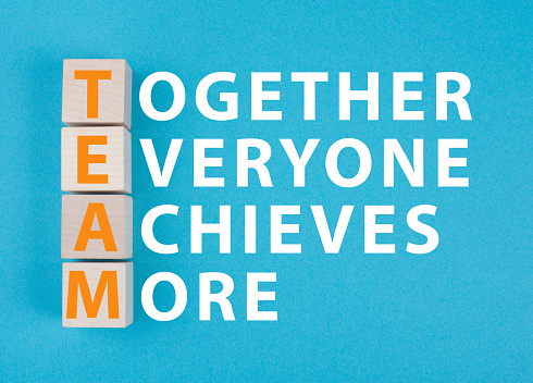 Team, together everyone achieves more is standing on a blue colored background, wooden cubes