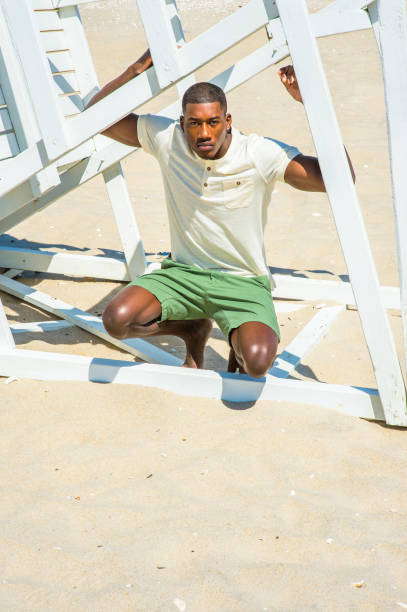 istock Young black man squatting on beach, relaxing 1346611565
