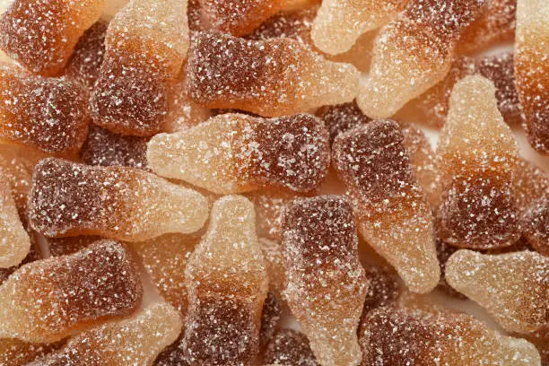 Photo of Cola-flavored chewable bottle-shaped gummy candies covered with sugar crystals