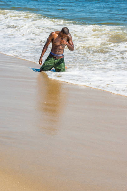 istock Young black man, shirtless, playing on beach 1346611924