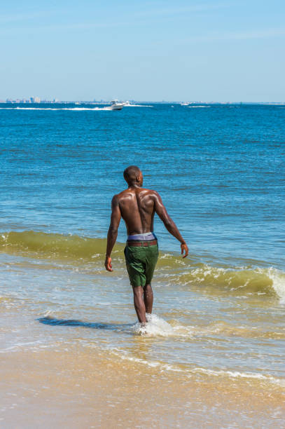 istock Young black man, shirtless, playing on beach 1346612533