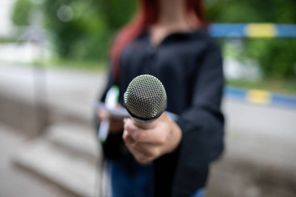 istock Journalist at news conference, writing notes, holding microphones 1346615047