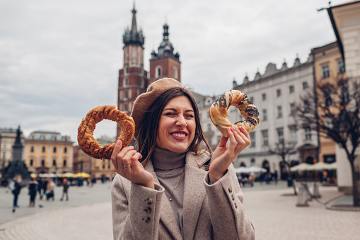 Mujer comiendo bagel obwarzanek bocadillo de cocina tradicional polaca en la plaza del mercado de Cracovia. Viaja por Europa en otoño photo