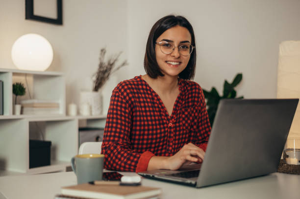 istock Beautiful woman using a laptop while working from home 1346618745