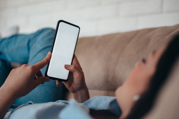 istock Woman using smartphone while lying on the couch at home 1346618753