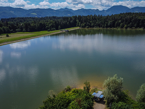 Panorama of Zovnesko jezero or Zovnek lake in Slovenia, on a hot summer day. Visible parked adventure camper van on the peninsula of the coast.