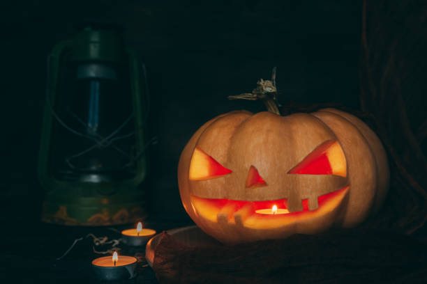 istock Halloween pumpkin, Jack O. Lantern Carved pumpkin on a board, a candle burns inside. 1346621564