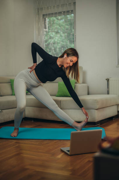 istock Woman training at home and doing fitness exercises while using laptop 1346621933