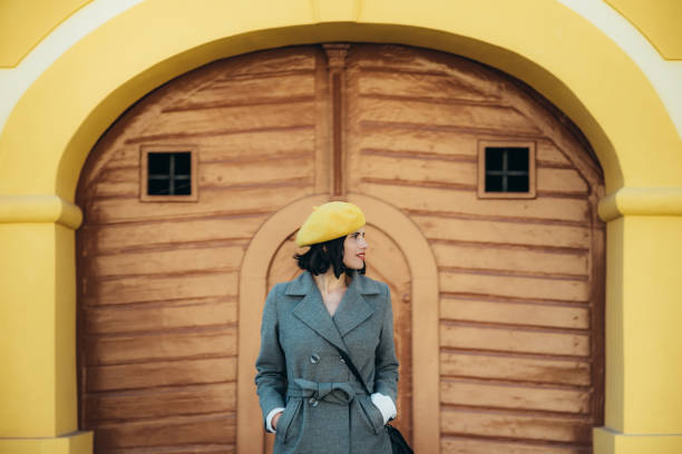 istock Woman using smartphone and wearing yellow beret and a gray coat 1346621956