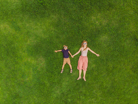 Mom and son are lying on the grass in the park, photos from the drone, quadracopter.