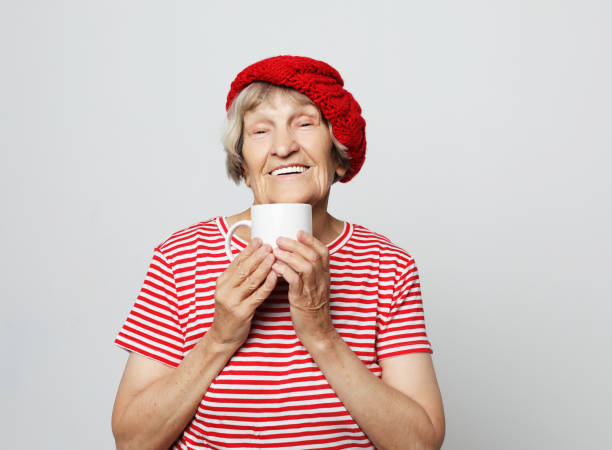 istock old excited lady smiling laughing, holding cup drinking coffee or tea 1346623407